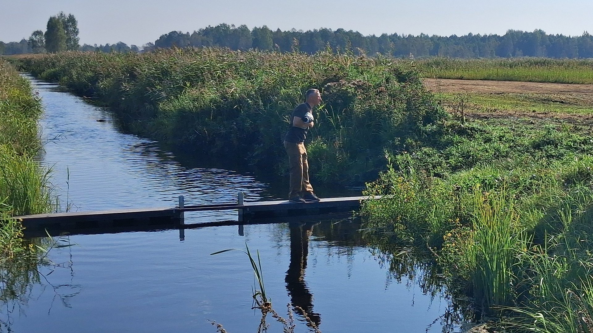 Men standing on weir in water next to peatland area